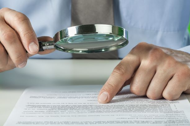 man reading the fine print on a liability waiver with magnifying glass